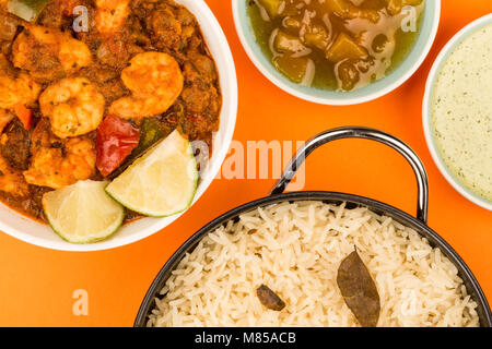 Indiano piccante re stile boreale Bhuna Curry contro uno sfondo arancione con riso Basmati chutney di mango e una salsa di immersione Foto Stock