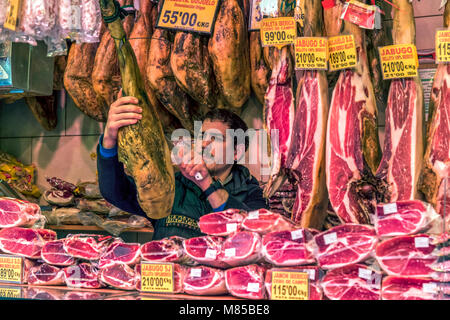 Drogheria durante il taglio di prosciutto spagnolo al Mercato di Boqueria, Barcellona, in Catalogna, Spagna Foto Stock