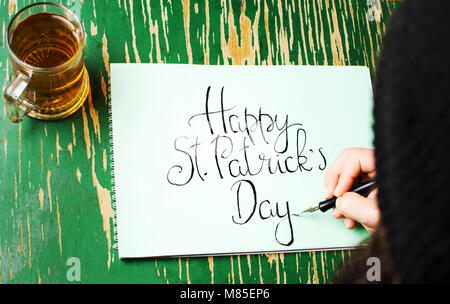 L'uomo la scrittura di un felice St Patrick giorno scheda di calligrafia Foto Stock