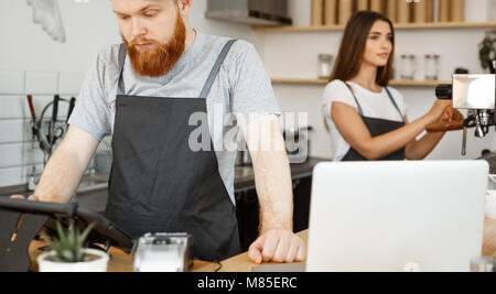 Caffè il concetto di Business - il giovane bello barbuto barman, barista manager o inviare l'ordine dalla valutazione in tavoletta digitale menu nella moderna caffetteria. Foto Stock