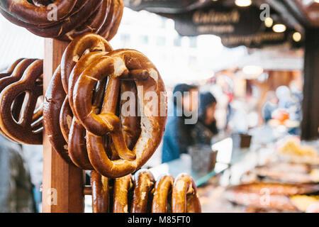 Celebrazione della tedesca famosa festa della birra Oktoberfest. Salatini tradizionale chiamato Brezel appendere sul supporto contro lo sfondo di una offuscata s Foto Stock