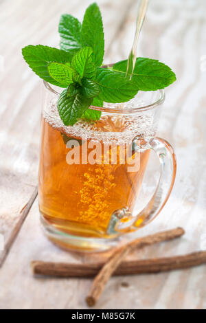 Arabo nana tè alla menta in vetro tradizionale con la menta, cannella, su un vecchio bianco bordo in legno Foto Stock