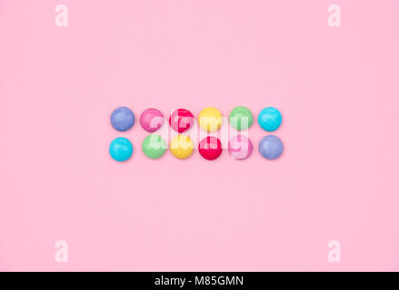 Un assortimento di caramelle colorate su sfondo rosa. Foto Stock