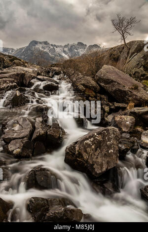 Una piccola cascata e scogli nelle vicinanze Llyn Idwal, Snowdonia, il Galles del Nord in un giorno nuvoloso in inverno Foto Stock