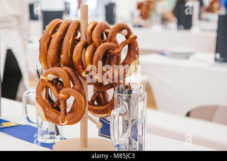 Celebrazione della tedesca famosa festa della birra Oktoberfest. Salatini tradizionale chiamato Brezel appendere sul supporto sul tavolo. In attesa di visitatori, c Foto Stock