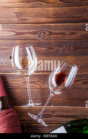 Immagine di due bottiglie di vino e bicchieri di vino su brown, sullo sfondo di legno. Foto Stock