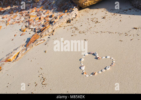 A forma di cuore da gusci si trova su una spiaggia di sabbia su Koh Samui Foto Stock