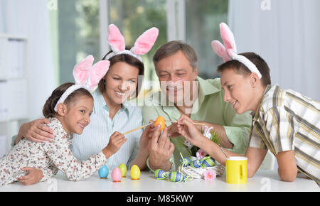 La famiglia felice di quattro indossando orecchie di coniglietto e pittura delle uova di Pasqua Foto Stock