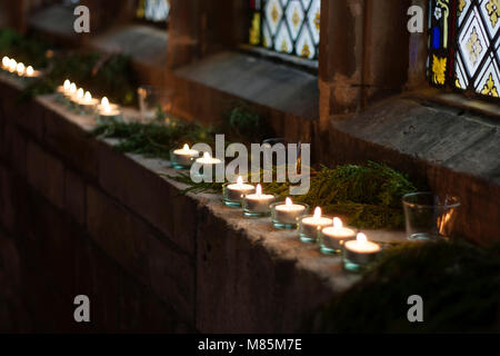 Tè atmosferica accendono le candele in una finestra della chiesa. Foto Stock