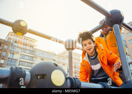 Dei bambini felici di arrampicata in un parco giochi urbano la costruzione in una giornata di sole Foto Stock