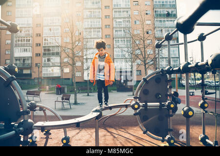 Carino piccolo ragazzo camminando la barra di bilanciamento in un parco giochi urbano in una giornata di sole Foto Stock