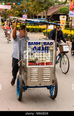 Un uomo spinge un camion vendere Banh Bao, un pane cotto a vapore snack, ad Hoi An, Vietnam Foto Stock