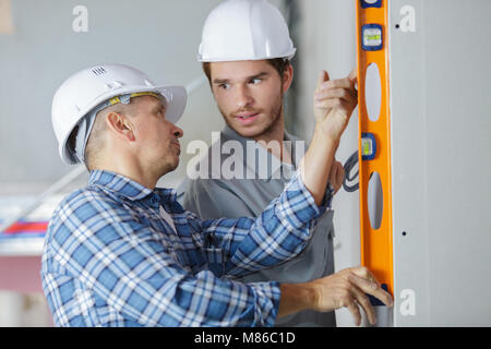 Operaio edile controlla il livello sulla parete Foto Stock