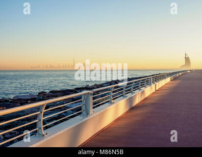 Palm Jumeirah Boardwalk e centro città Skyline di sunrise, Dubai, Emirati Arabi Uniti Foto Stock