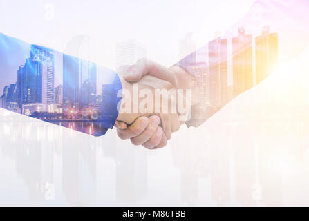 Immagine a doppia esposizione di un imprenditore handshake sulla vita notturna della città sullo sfondo. Il concetto di partenariato d'affari. Foto Stock