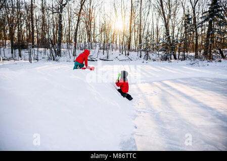 Due ragazzi che giocano sulla neve da un lago ghiacciato Foto Stock