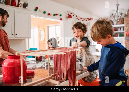 Padre fare la pasta con i suoi tre figli Foto Stock