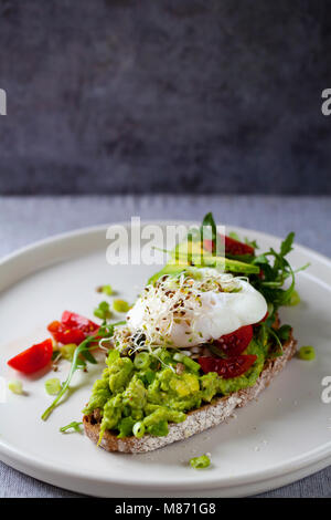 La segala toast con avocado, pomodori, germogli alfalfa e Uovo affogato Foto Stock