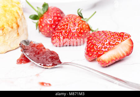 Tè alla crema - scones con marmellata e crema, servito con una tazza di tè su sfondo bianco Foto Stock