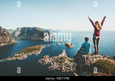 Giovane famiglia che viaggiano insieme sulla scogliera edge in Norvegia l uomo e la donna il concetto di stile di vita le vacanze estive all'aperto vista aerea Isole Lofoten Reinebri Foto Stock