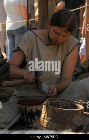 Uomo di dimostrare la frantumazione del minerale di ferro per uso in bloomery al Festival archeologico Dymarki Swietokrzyskie. Nowa Slupia, Polonia, 21-22 agosto 2010. Foto Stock