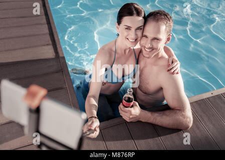 Vista dall'alto sulla coppia rilassata tenendo selfies in piscina Foto Stock