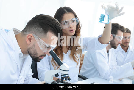 Gli scienziati di esaminare attentamente la pipetta con fluido blu in laboratorio Foto Stock