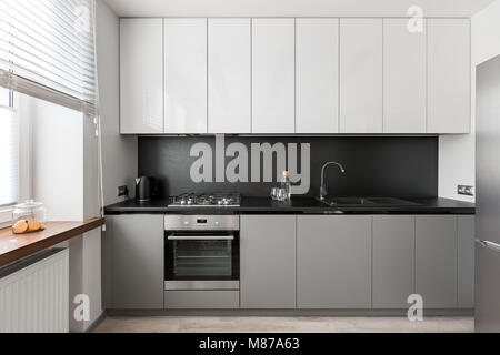 Moderno ed elegante interno con piano di lavoro nero, grigio e bianco unità di cottura Foto Stock
