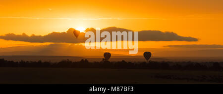 Il palloncino al di sopra del Masai Mara a sunrise. Tre palloncini bassa deriva nella savana all'alba. Banner panoramica in popular socila media dimensioni. Foto Stock