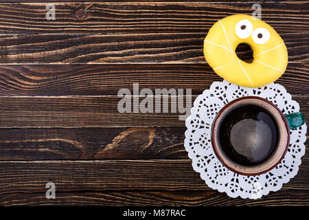 Tazza di caffè e ciambelle su un tavolo di legno. La colazione oncept. Vista superiore, spazio di copia Foto Stock