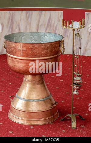 Battesimo ortodosso ciotola di acqua santa e candele in battistero Foto Stock