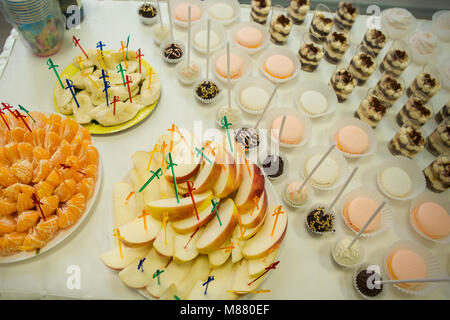 Frutti assortiti con spiedini e gustosi dolci serviti sulla tavola bianco Foto Stock