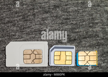 Serie di mini e micro e nano simcard. Isolato su tessuto grigio Sfondo texture Foto Stock