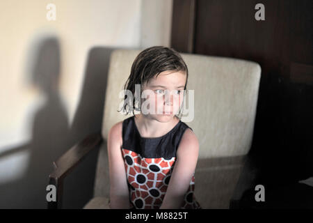 7 anno vecchio ragazza seduta da solo con i capelli umidi Foto Stock