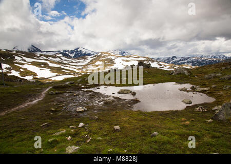 Ampia vista panoramica sulle montagne ricoperte di neve con un laghetto in primo piano Foto Stock