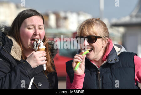 Brighton Regno Unito 16 marzo 2018 - Visitatori godere di un gelato e di un bastone di roccia nel caldo sole sul lungomare di Brighton oggi ma il meteo Le previsioni per girare nuovamente a freddo con neve previsto in alcuni pezzi la Gran Bretagna per il fine settimana fotografia scattata da Simon Dack Credito: Simon Dack/Alamy Live News Credito: Simon Dack/Alamy Live News Foto Stock