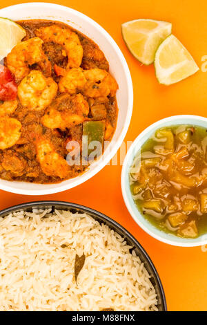 Indiano piccante re stile boreale Bhuna Curry contro uno sfondo arancione con riso Basmati e chutney di mango Foto Stock