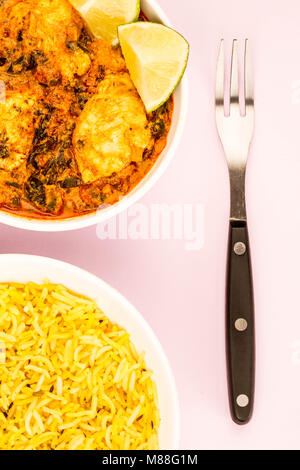 In stile indiano Saag pollo Masala Curry contro un sfondo rosa con riso pilaf e una forcella Foto Stock