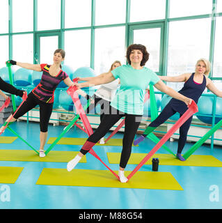 Il 50-anno donna facendo esercizio con lattice banda fitness durante gli allenamenti in palestra. Foto Stock