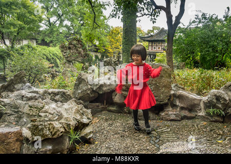 Piccola ragazza in abito rosso Dancing in the Rain, Liu Yuan giardino classico, Souzhou, Cina Foto Stock