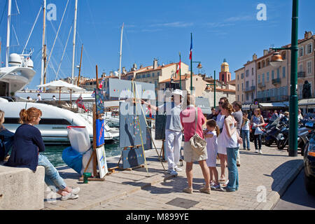 Pittore mostra i suoi dipinti a passeggiare lungomare al porto di Saint-Tropez, riviera francese, il sud della Francia, Cote d'Azur, in Francia, in Europa Foto Stock