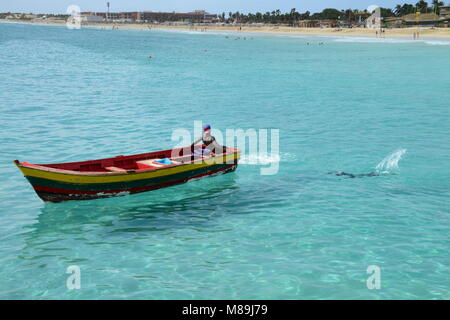 Un maschio si rilassa sulla sua barca mentre un altro maschio nuota vicino, vicino a spiaggia di Santa Maria, sull isola di Sal, in Capo Verde (un ex colonia portoghese). Foto Stock