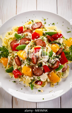 Pasta con salsicce e verdure sul tavolo di legno Foto Stock