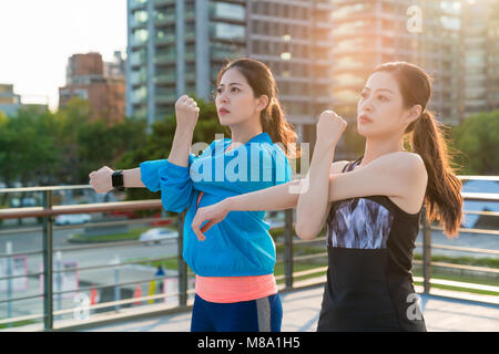 Due asian atlete di fare stretching dopo l'esecuzione di allenamento. Uno stile di vita attivo nella città. Foto Stock