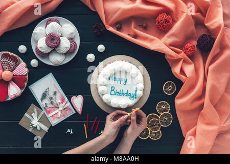 Donna mettendo la candela sulla torta di compleanno Foto Stock