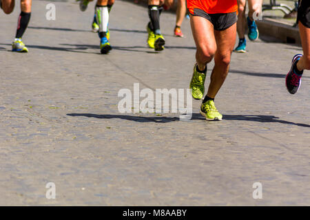 Dettaglio di un gruppo di corridori durante una maratona della città. Gambe e scarpe da ginnastica. Muscoli sotto stress. Sport concept Foto Stock