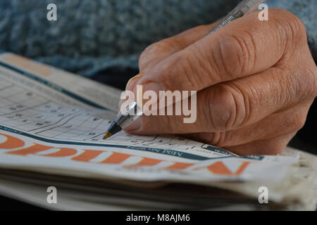 Close up uomo senior facendo un puzzle Sudoku, il fuoco selettivo sulla penna pennino. Foto Stock