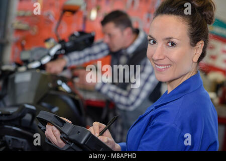 Donna meccanico riparazione di un motociclo in un workshop Foto Stock