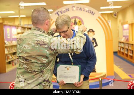 Il comando Sgt. Il Mag. Sarà Holland, comando sergente maggiore degli STATI UNITI Army Garrison Giappone, awards James Lacombe, di vigilanza bibliotecario al Camp Zama, libreria con i Comandanti di un premio per il servizio civile di Febbraio 22, 2018 durante la grande cerimonia di apertura della biblioteca stazione teen. (U.S. Esercito Foto Stock