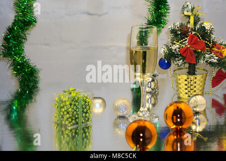 Biglietto di auguri fatto di natale e yew anno decorazione sfere, tinsel, candela e due bicchieri di champagne con la riflessione, spazio copia, orizzontale vie Foto Stock